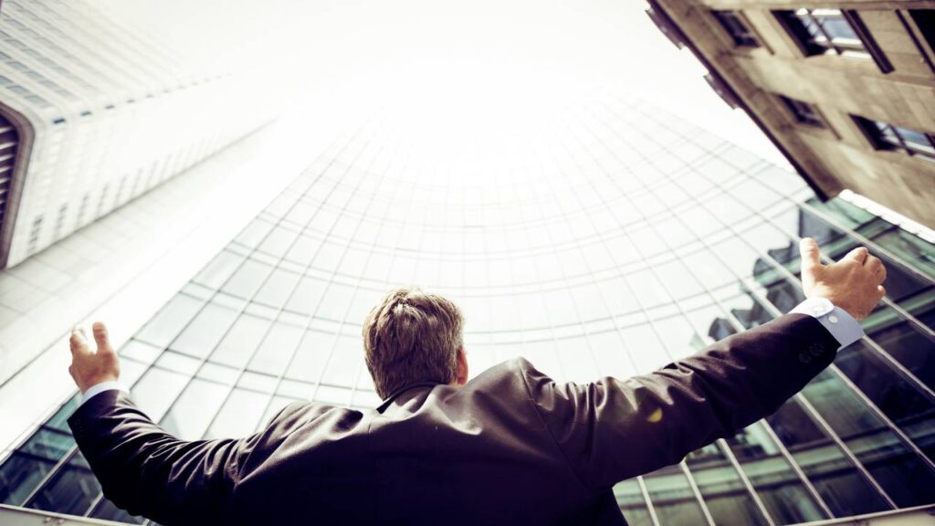 A businessman looking at the sky with spread arms