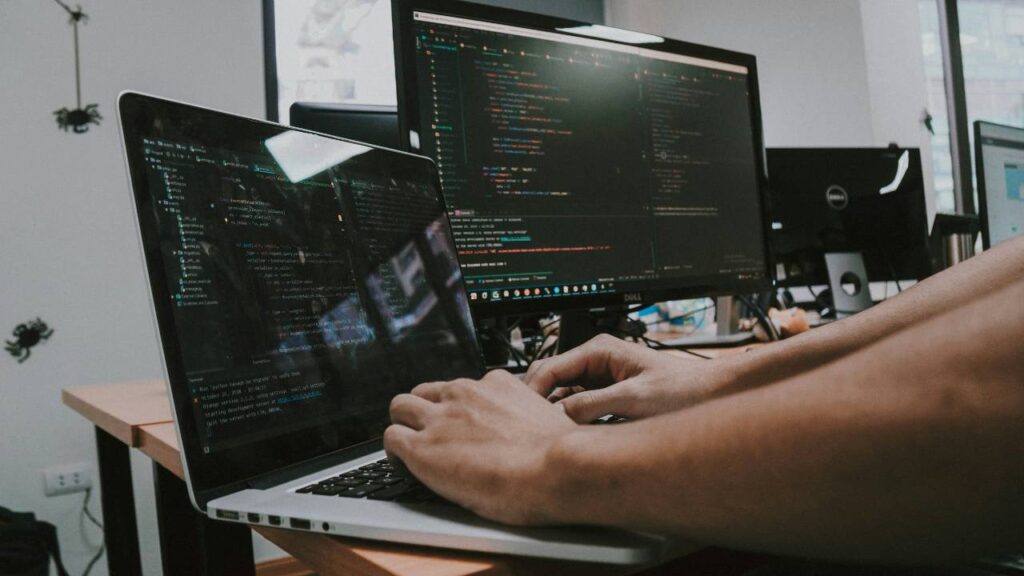 A man using a laptop and a desktop computer at the same time