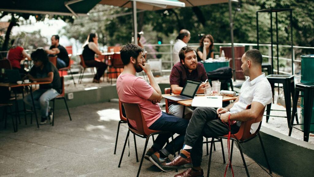 A group of three men sitting outdoors in a café 