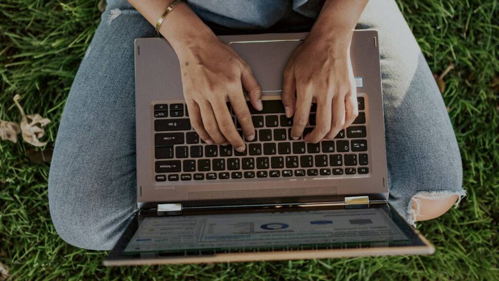 A photo of a woman using a laptop outside
