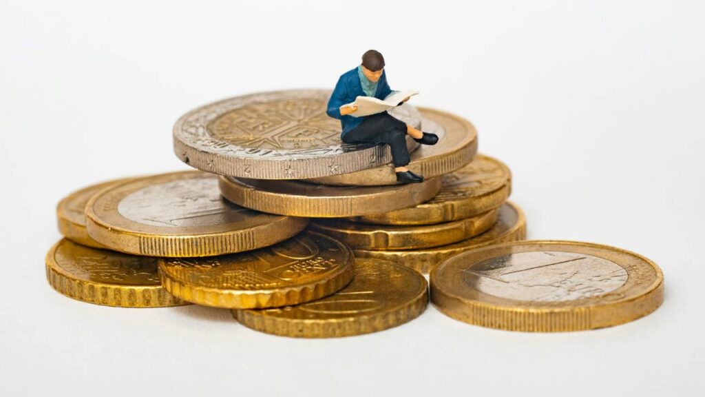 A figurine of a man reading newspapers placed on a stack of Euro coins