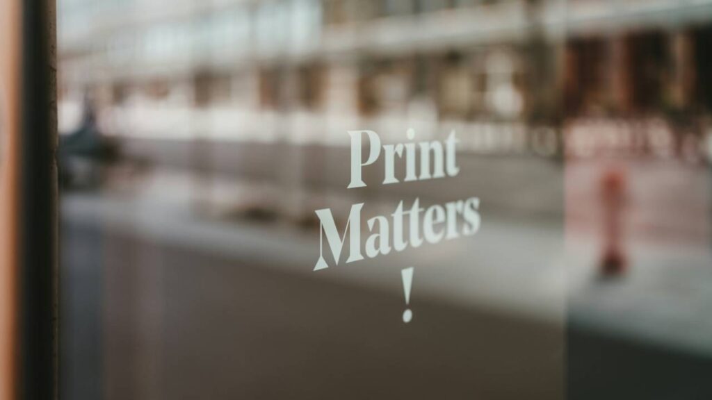 A photo of a sign saying "print matters!" on a glass door
