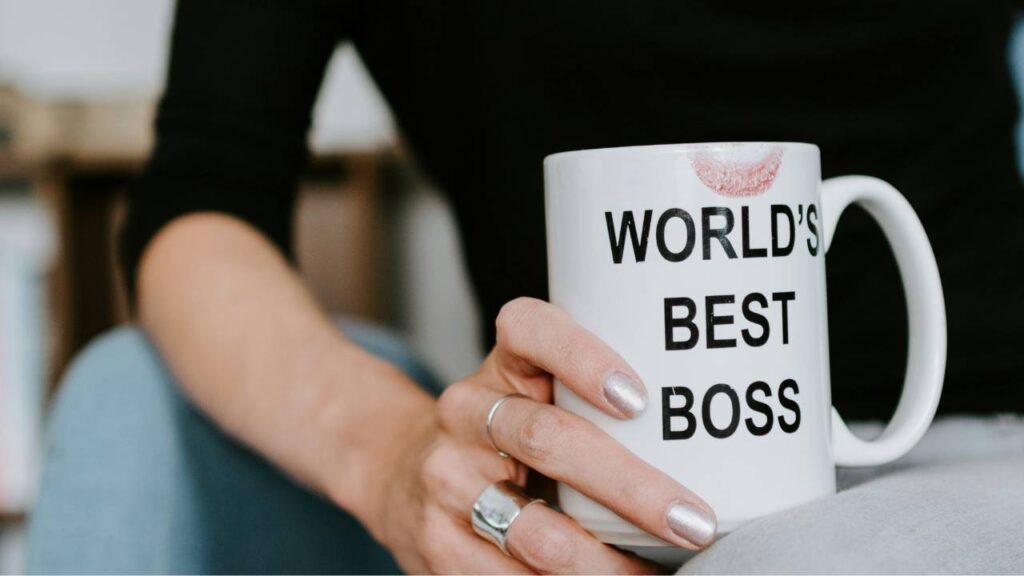 A close-up photo of a woman holding a cup with "world's best boss" written on it