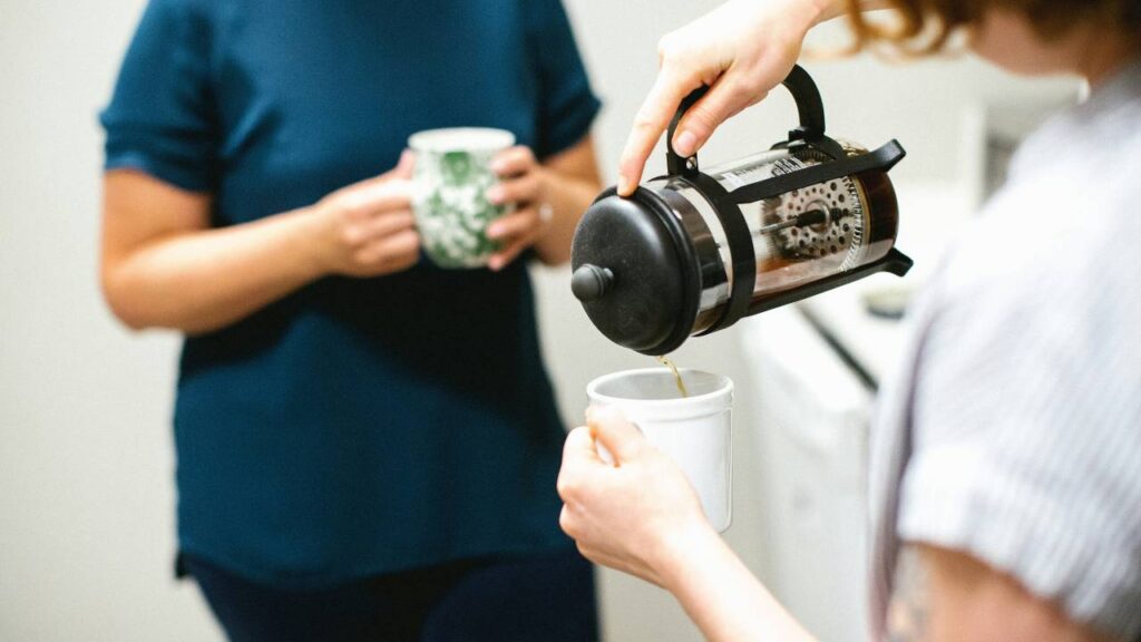 Two female workers sipping coffee in the office kitchen