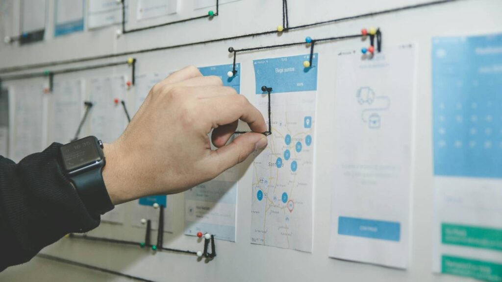 Man coming up with a plan by using notes and pins on a whiteboard