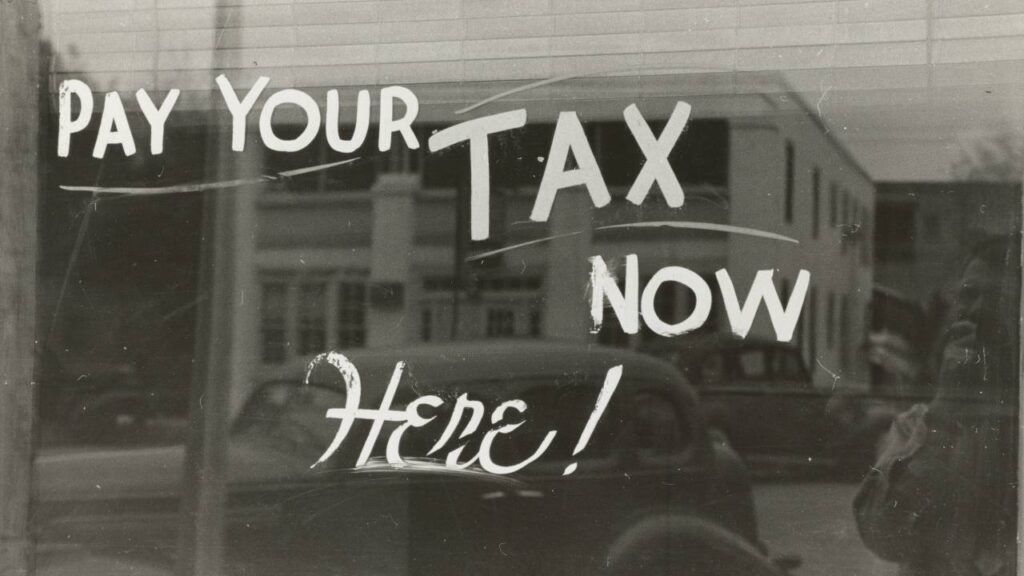 A 1930s window sign saying "pay your tax now here" 