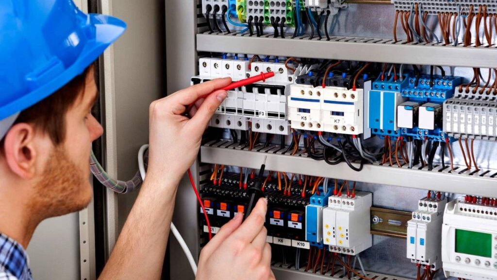 An electrician wearing a blue helmet inspecting electrical components 