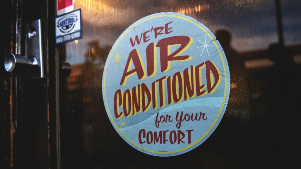 A door sign saying "We're air conditioned for your comfort" 