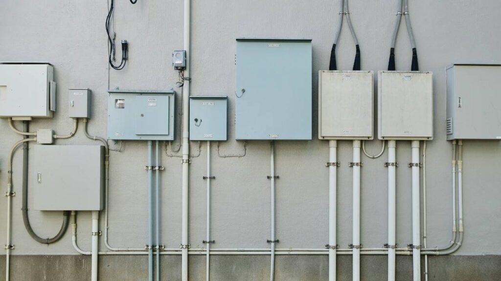 A white wall with several electrical boxes on it