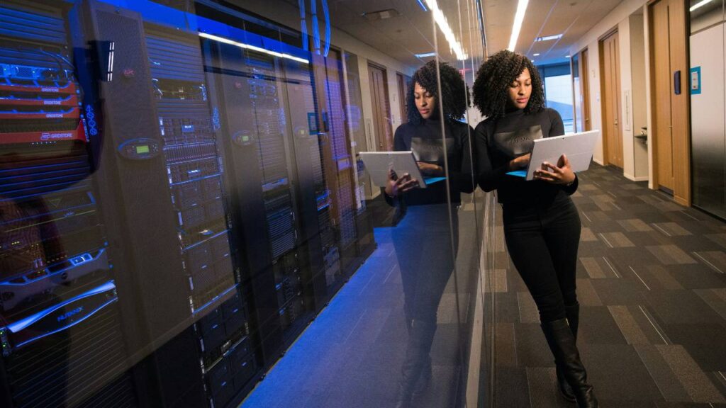 A woman using her laptop next to a server room
